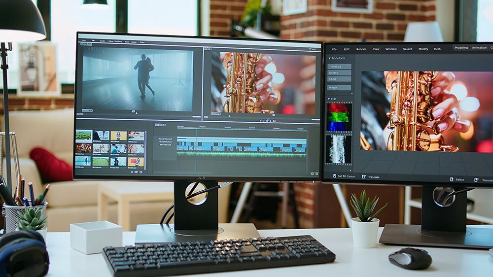 Dual-monitor desktop setup with keyboard and plant on a white desk, displaying video editing software.