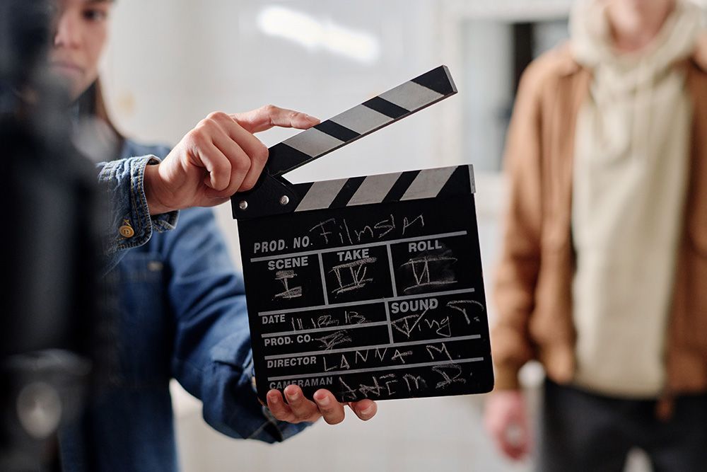 Film clapperboard held in front of a blurred crew on a movie set