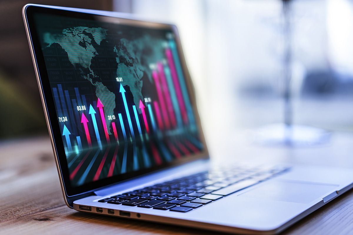 Laptop displaying colorful financial charts and graphs on a desk