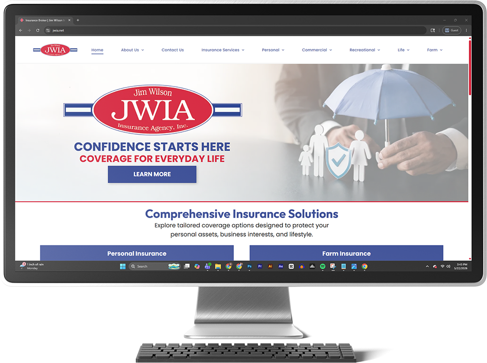 Desktop monitor showing JWIA insurance website with umbrella graphic and family under hands, blue and red header