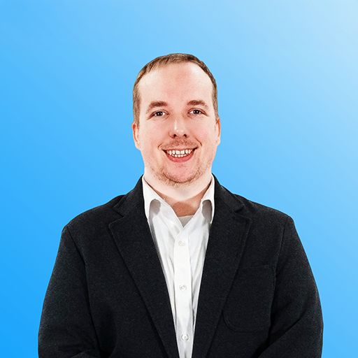 Man in a black suit smiling against a bright blue background