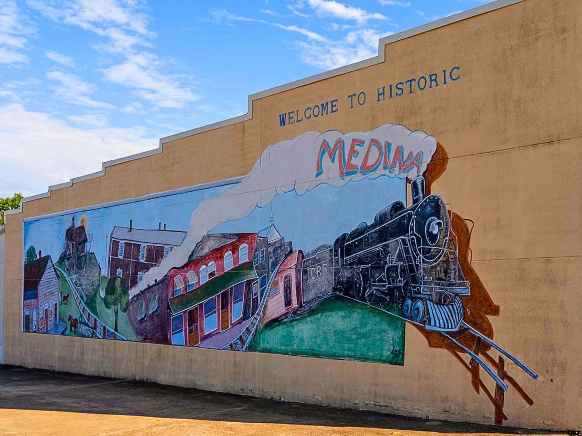 Mural on beige wall reading “Welcome to Historic Media,” with colorful train and town scenes under a blue sky