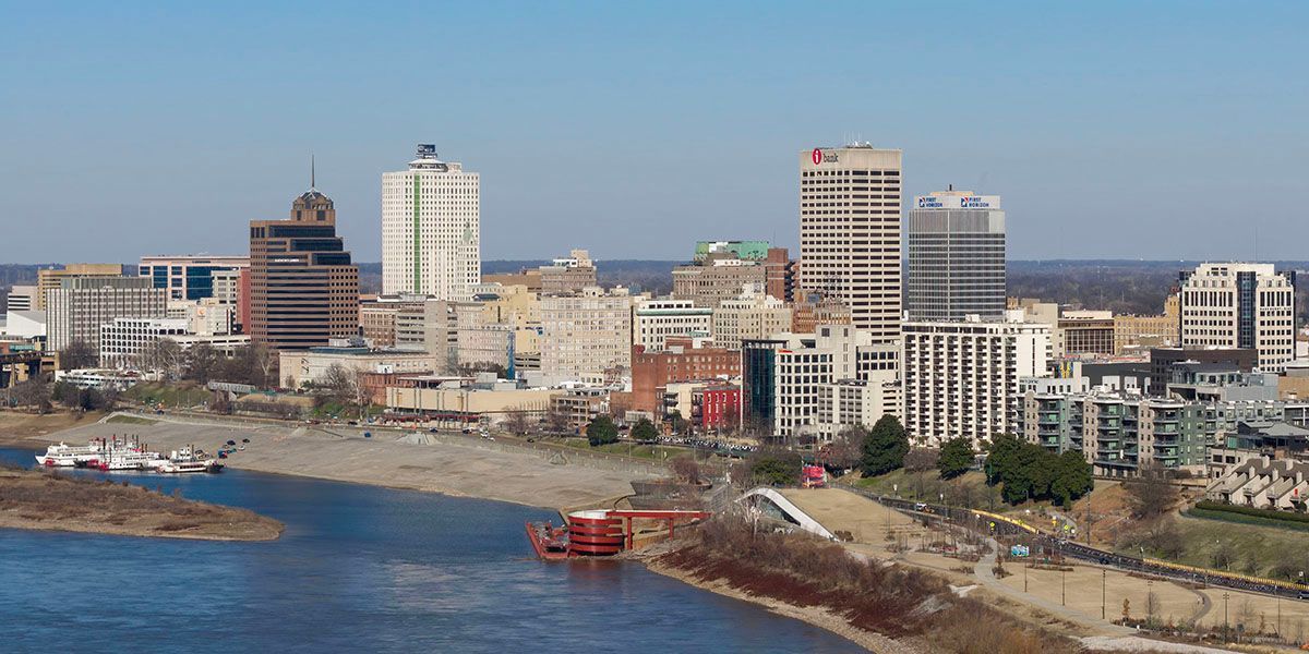 Coastal city skyline with tall buildings, waterfront, and blue water under a clear sky
