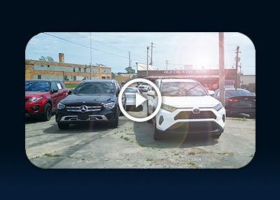 Two SUVs parked side by side in a lot, one black and one white, with a play icon overlay