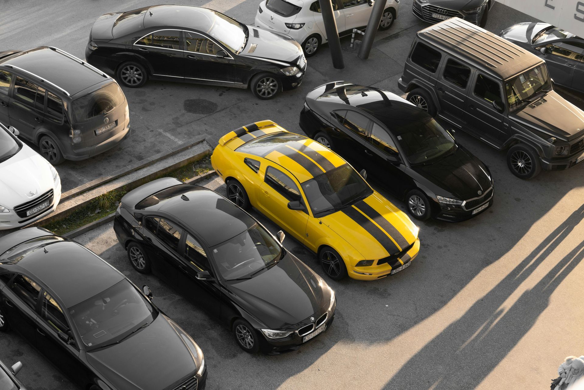 Overhead view of several parked cars, including a bright yellow sports car in a crowded lot
