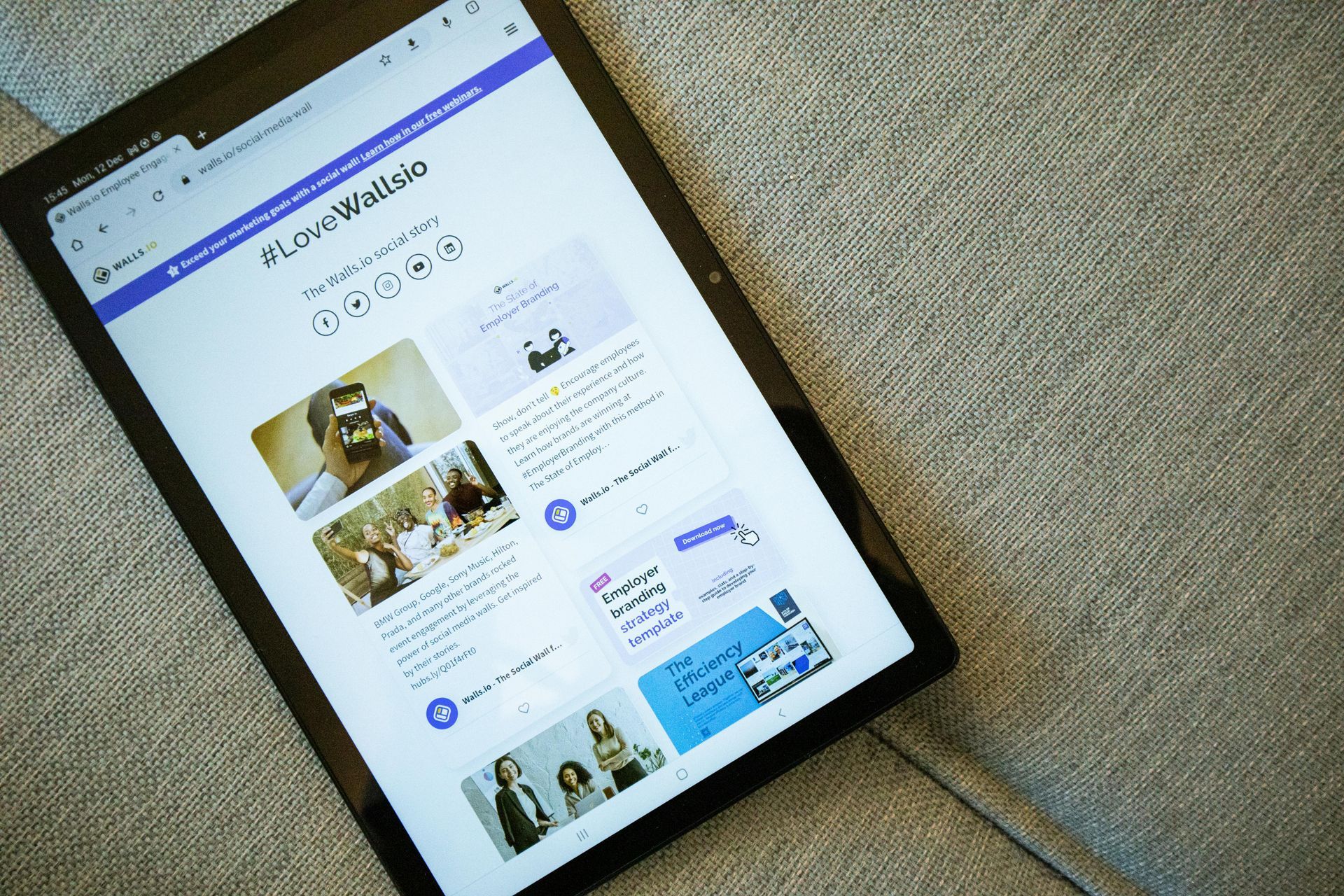 Tablet showing a website with photos and text on a white page, viewed at an angle on carpet.
