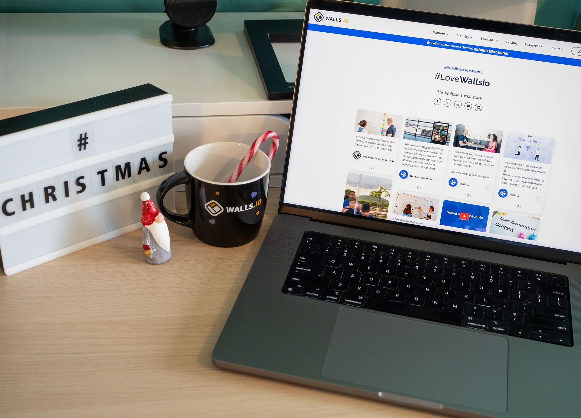 Desk with a laptop displaying a website, a Christmas lightbox, mug, and candy cane decoration