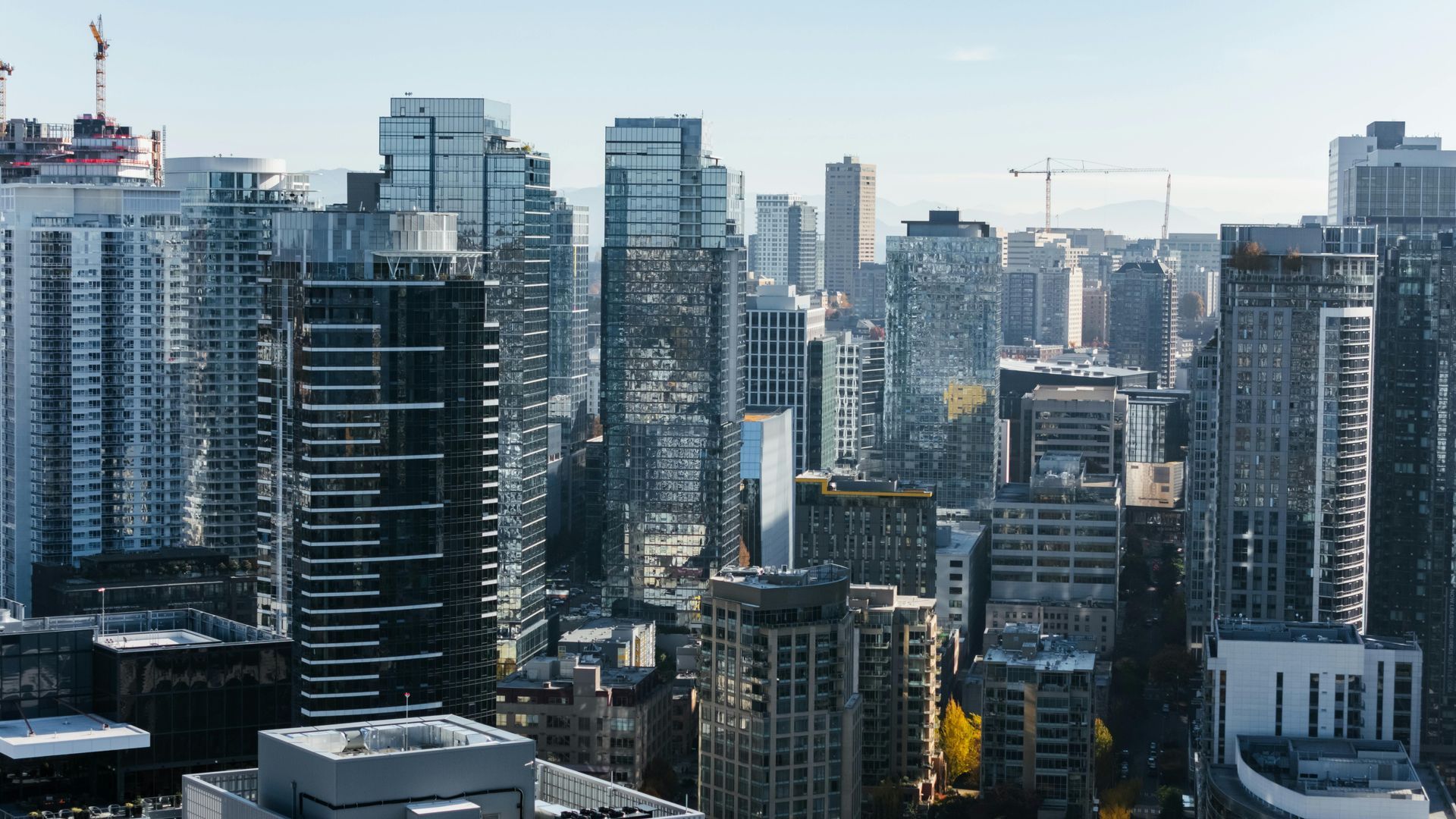 Dense modern city skyline with tall glass-and-steel buildings under a clear sky.