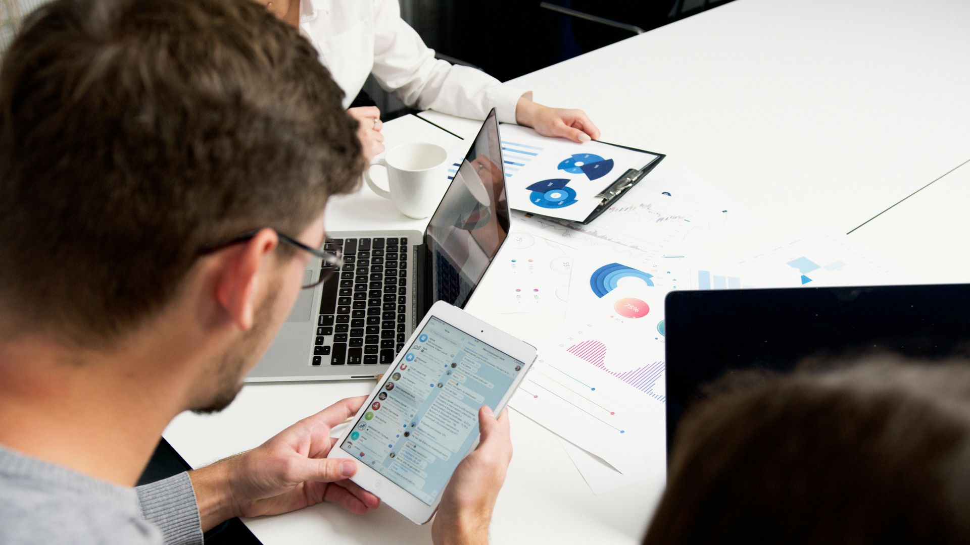 Tablet displaying analytics charts on a desk beside a white coffee cup.