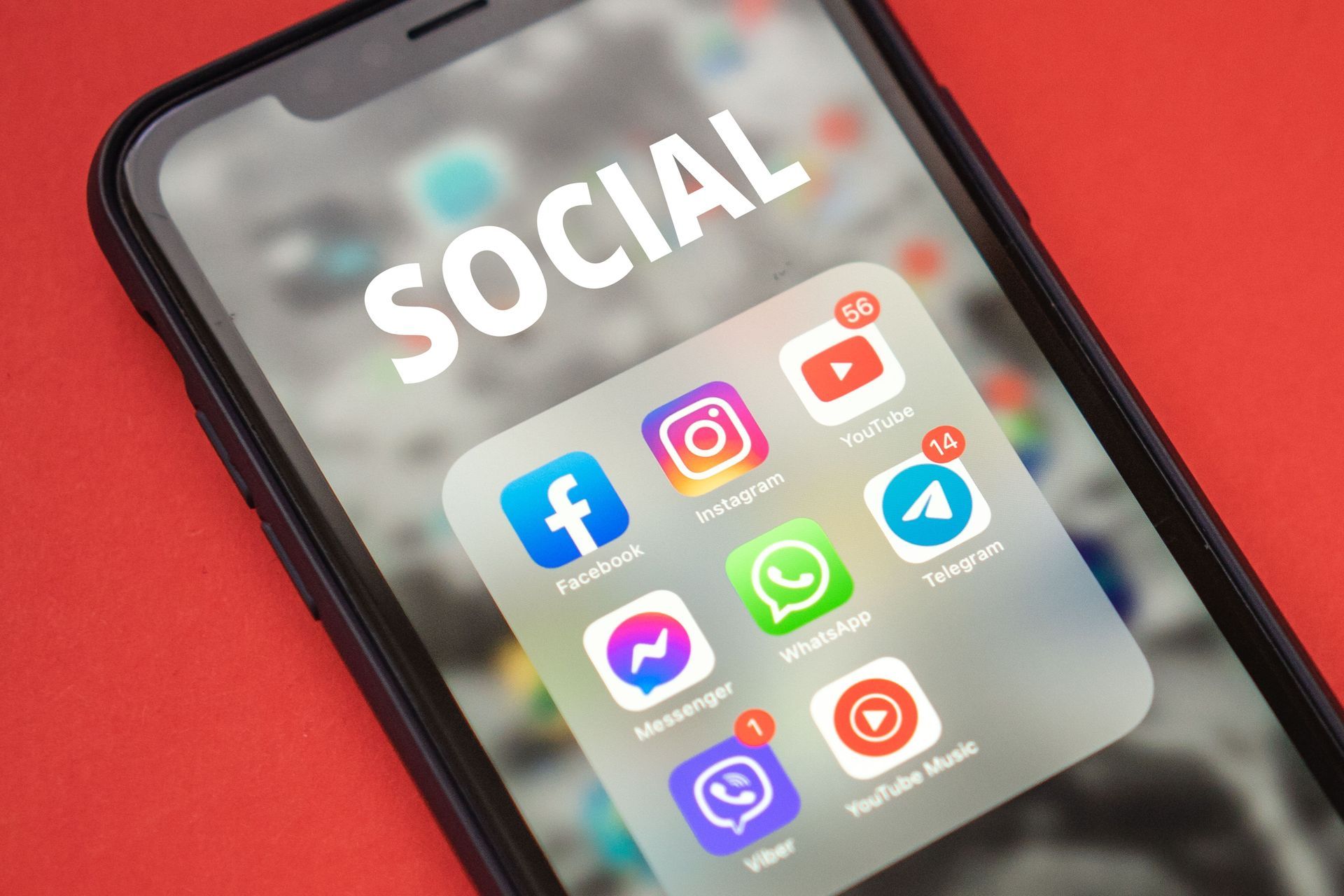 Smartphone displaying social media app icons on a red background with the word “SOCIAL”