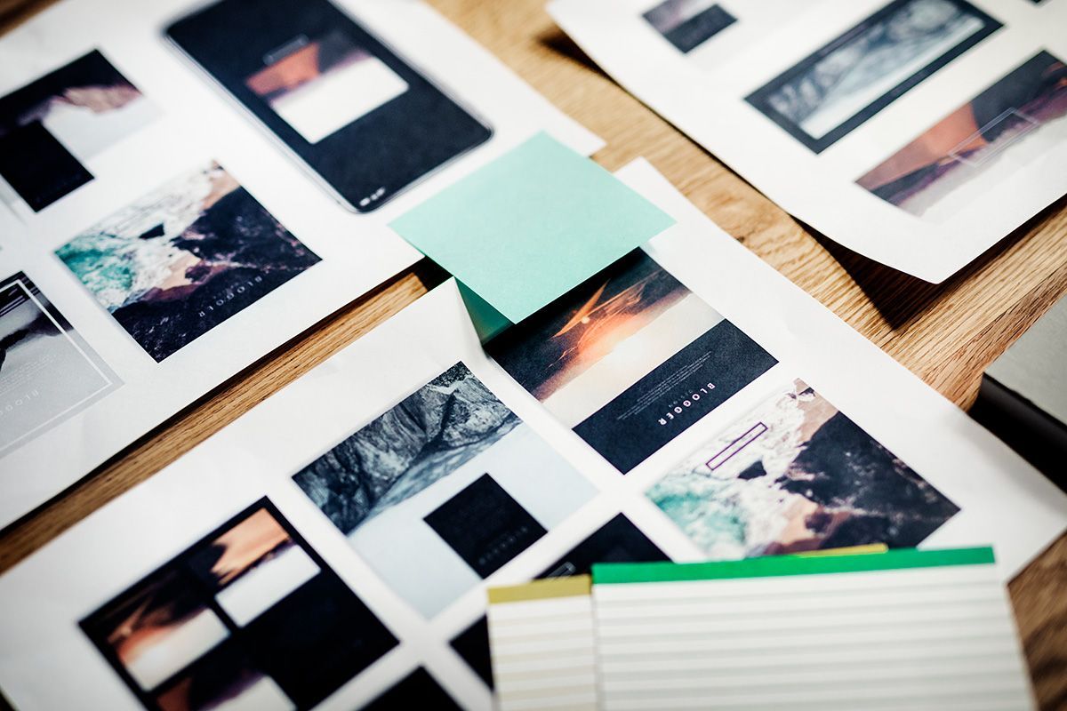 Scattered printed photos and notebooks on a desk, with a mint sticky note in the center