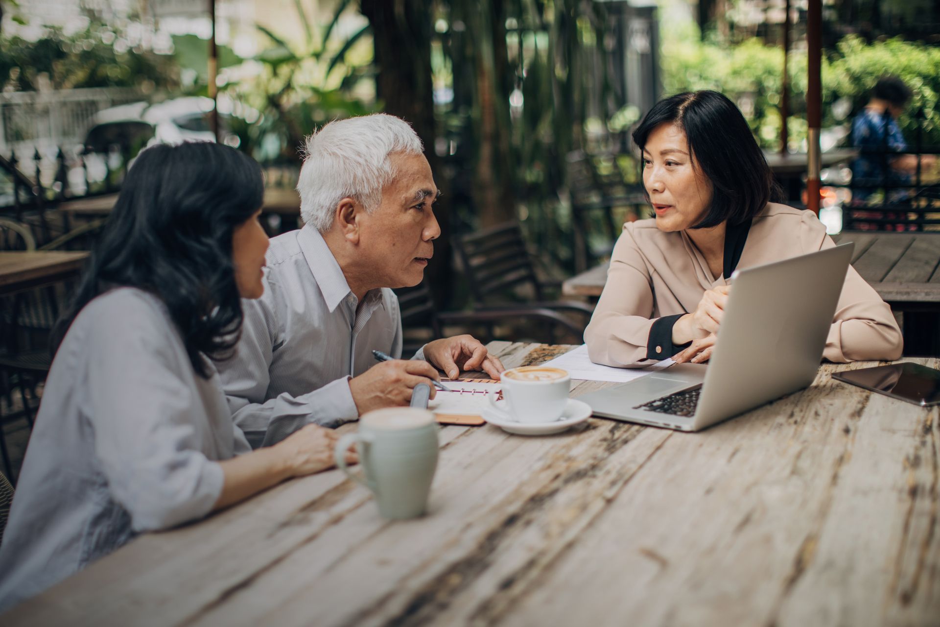 A group of people are sitting at a table looking at a laptop.