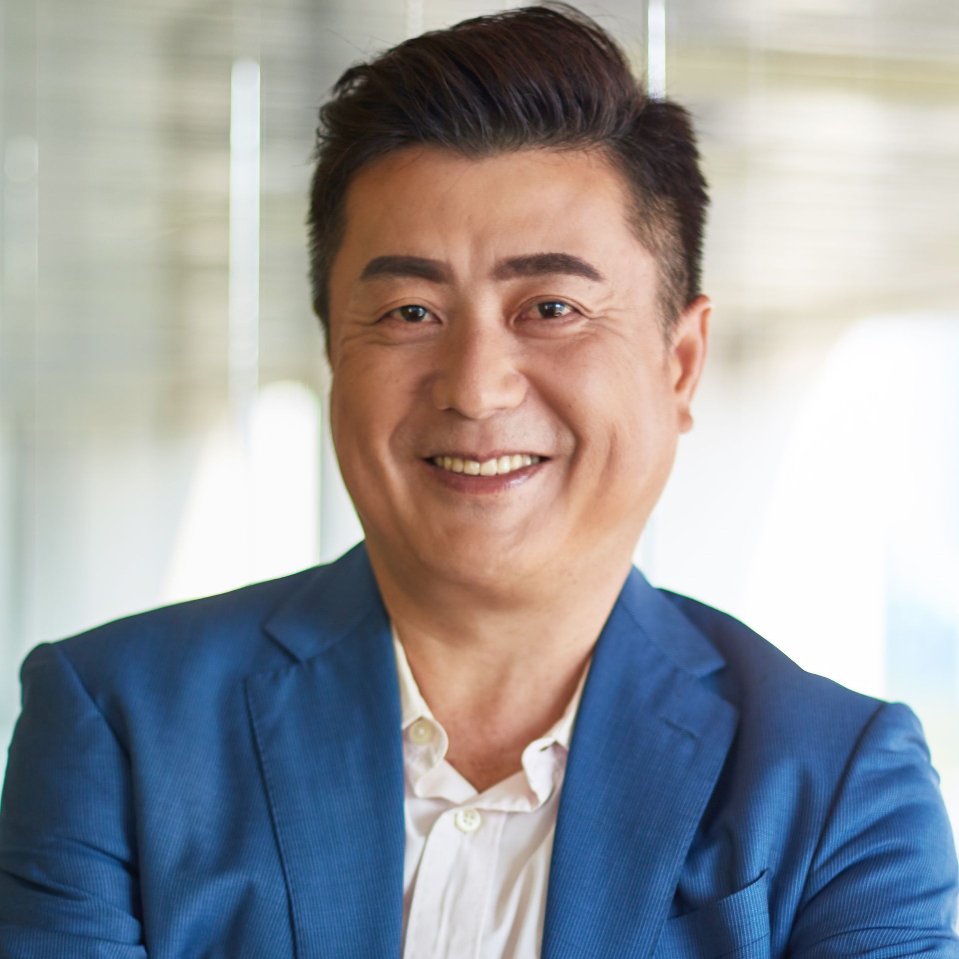 A man in a blue suit and white shirt is smiling for the camera.