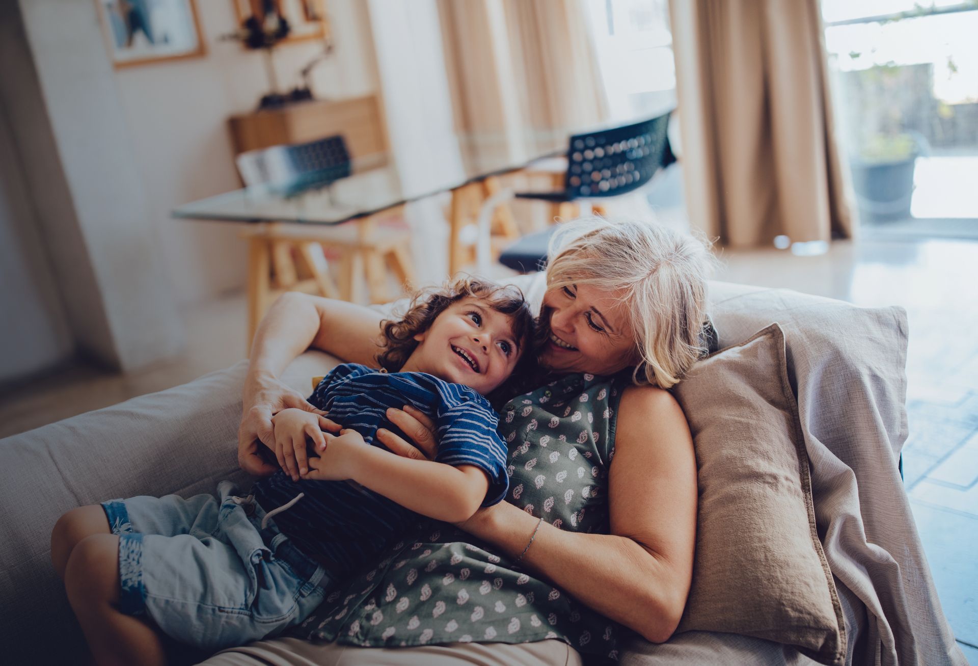 A woman is laying on a couch holding a child.
