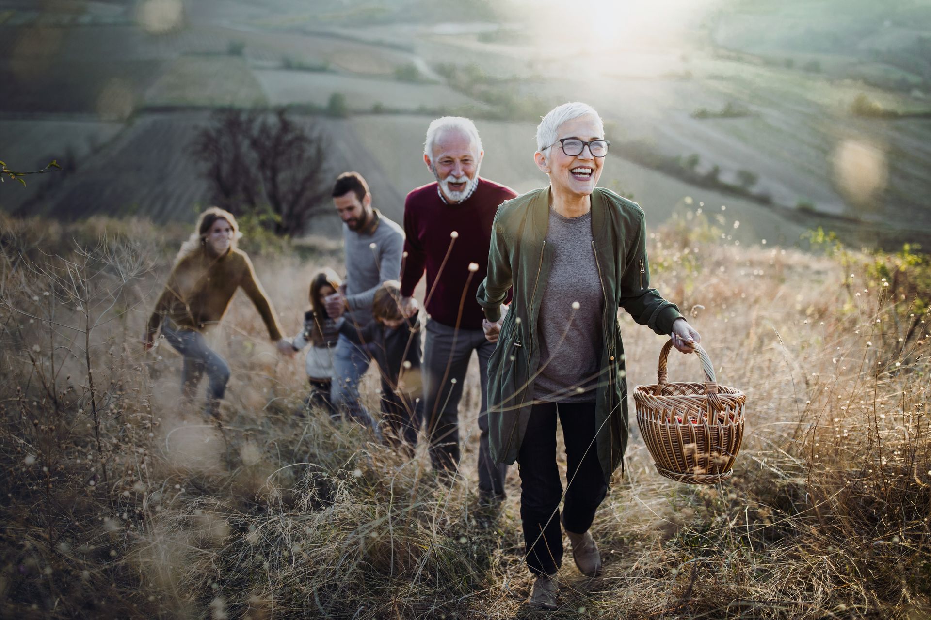 A family is hiking up a hill in a field.
