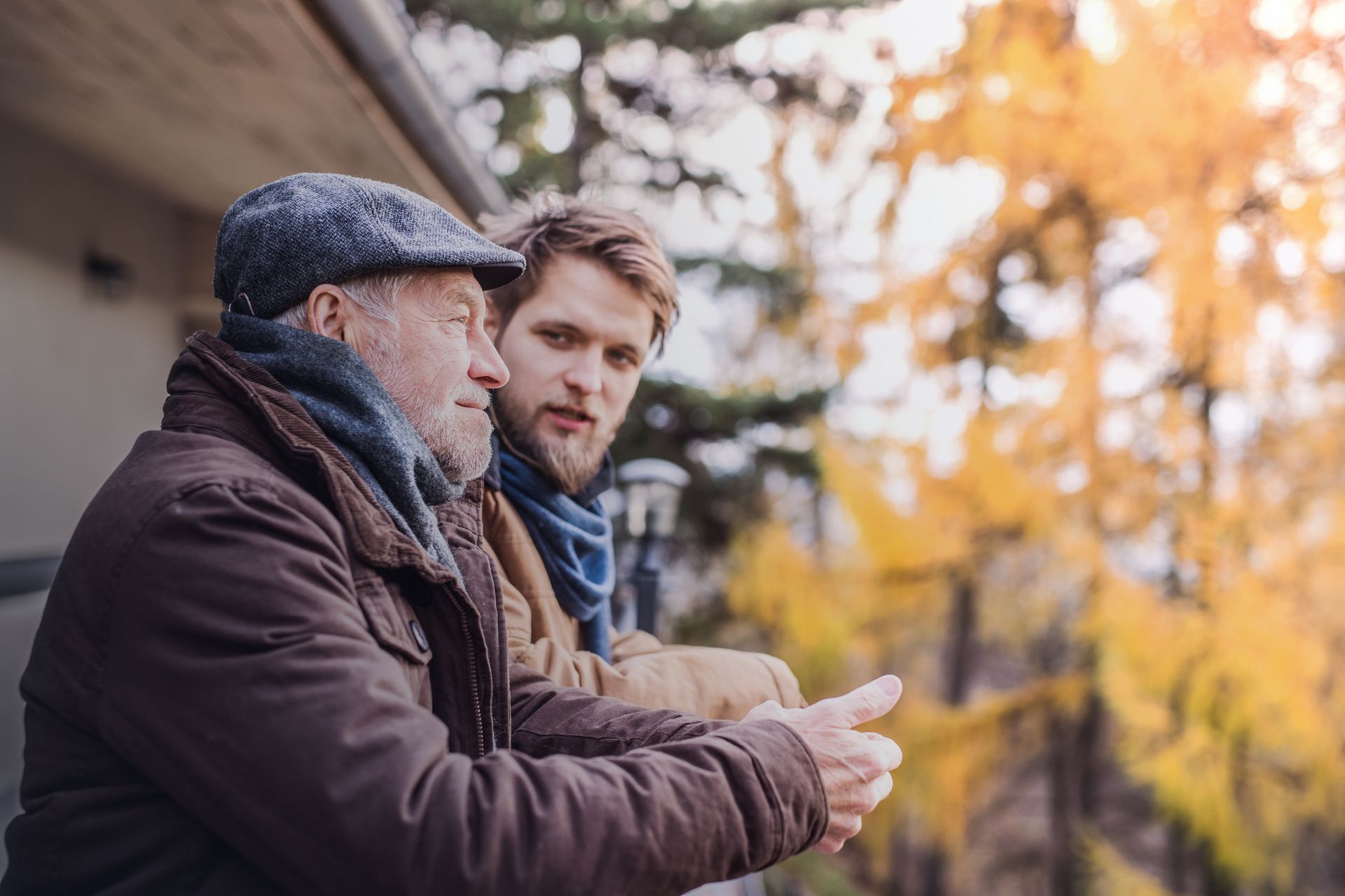 An older man and a younger man are standing next to each other on a balcony.