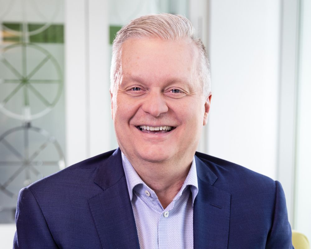 A man in a suit and white shirt is smiling for the camera.