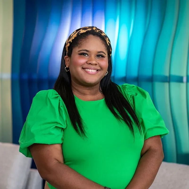 Smiling woman in a bright green dress standing before a blue and teal studio backdrop