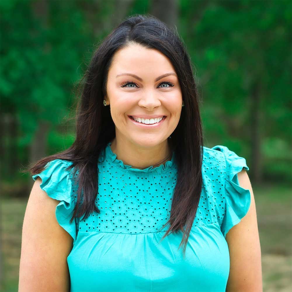 A smiling person wearing a turquoise ruffled sleeveless top