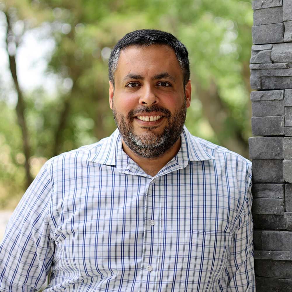 A man with a beard, wearing a blue and white plaid shirt