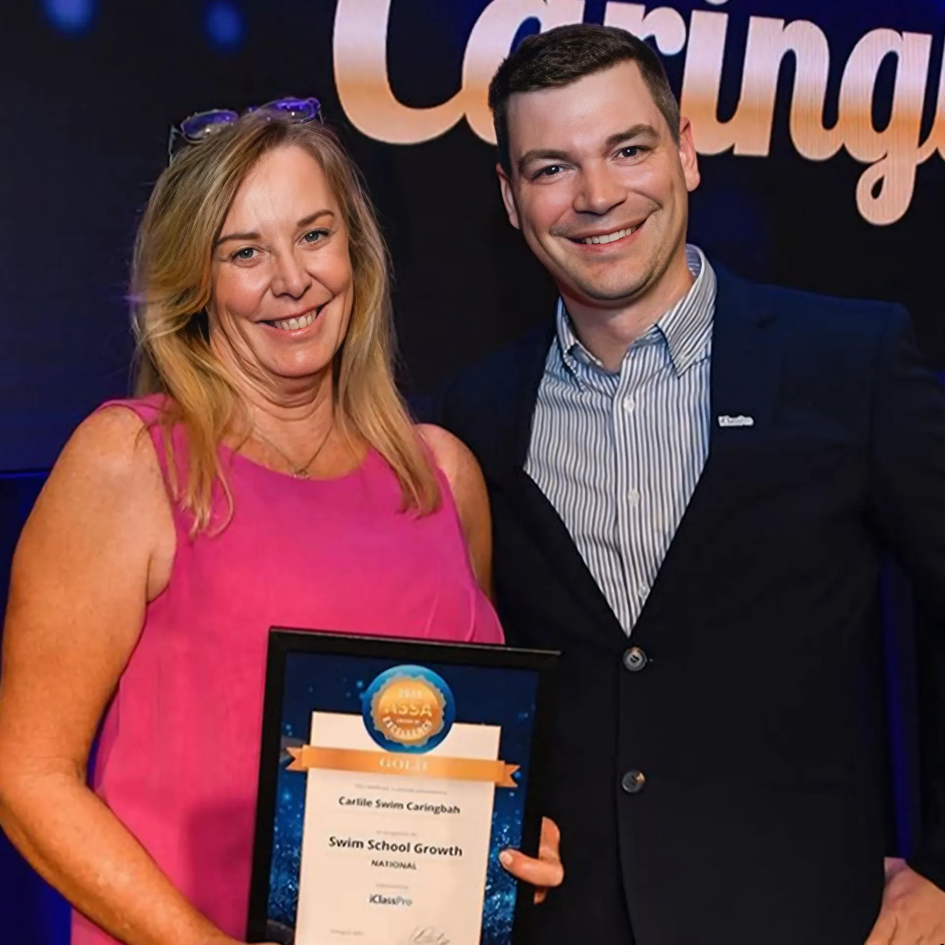A person in a pink top holding an award certificate