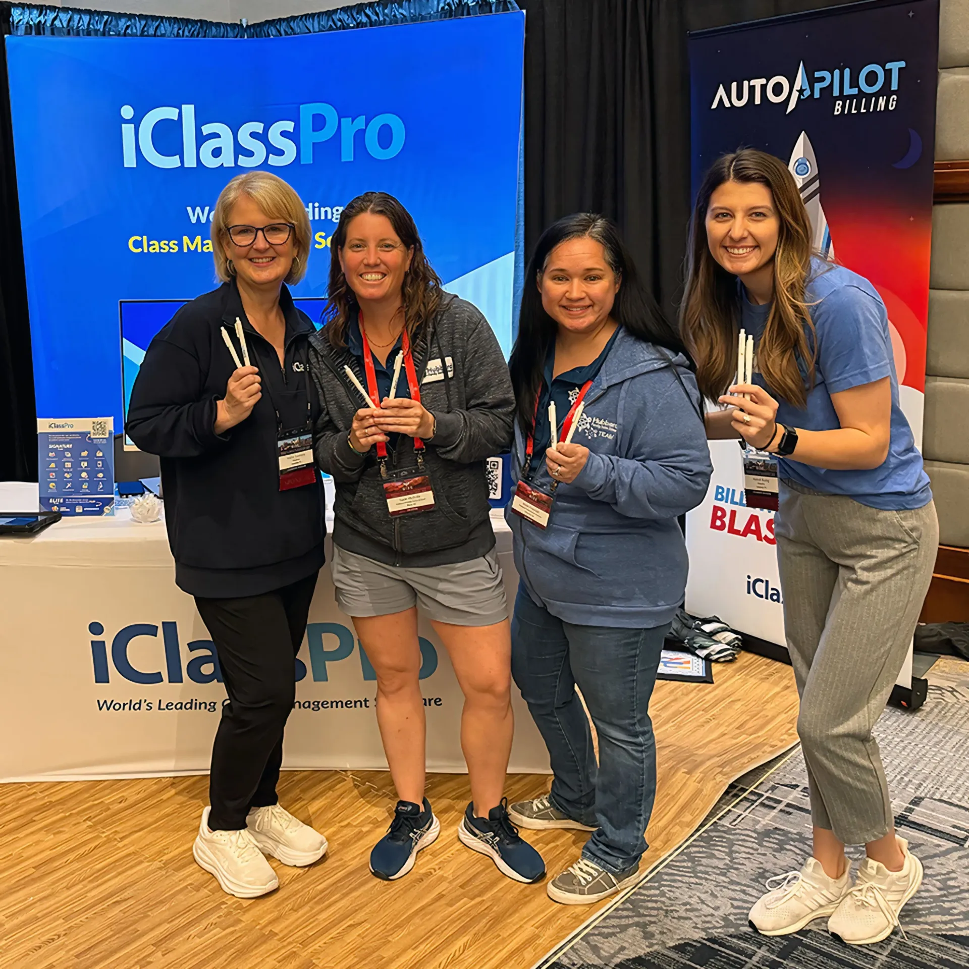Four people stand smiling in front of branded event booths