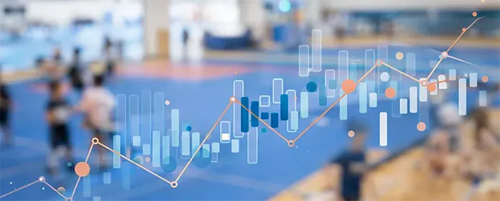 Stock chart overlaid on blurred people in a gym, suggesting financial trends in sports.