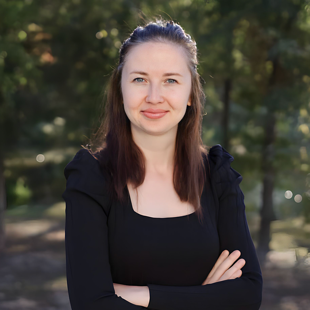 A person with long brown hair, wearing a black long-sleeved shirt