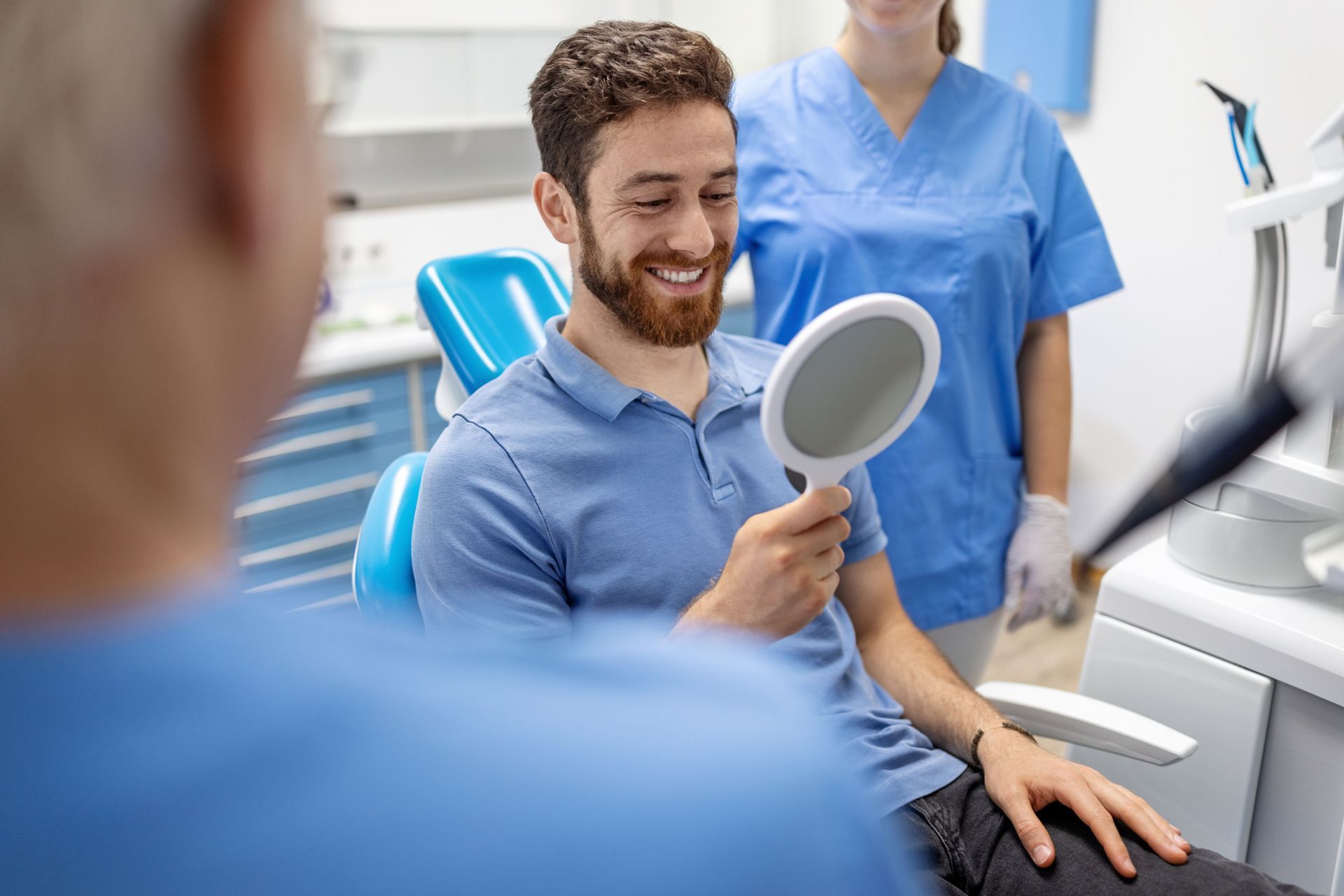 A patient is admiring his smile in a mirror post-treatment.
