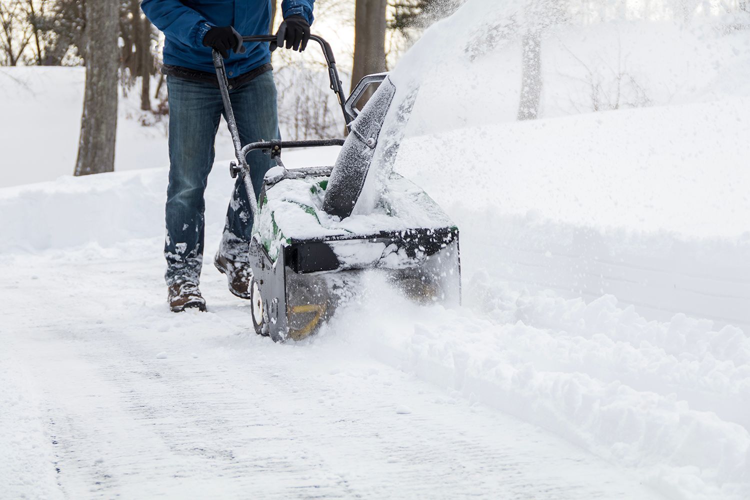 Person using a snow blower to clear a snow-covered driveway