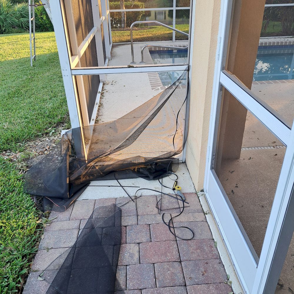A screened in porch with a pool in the background