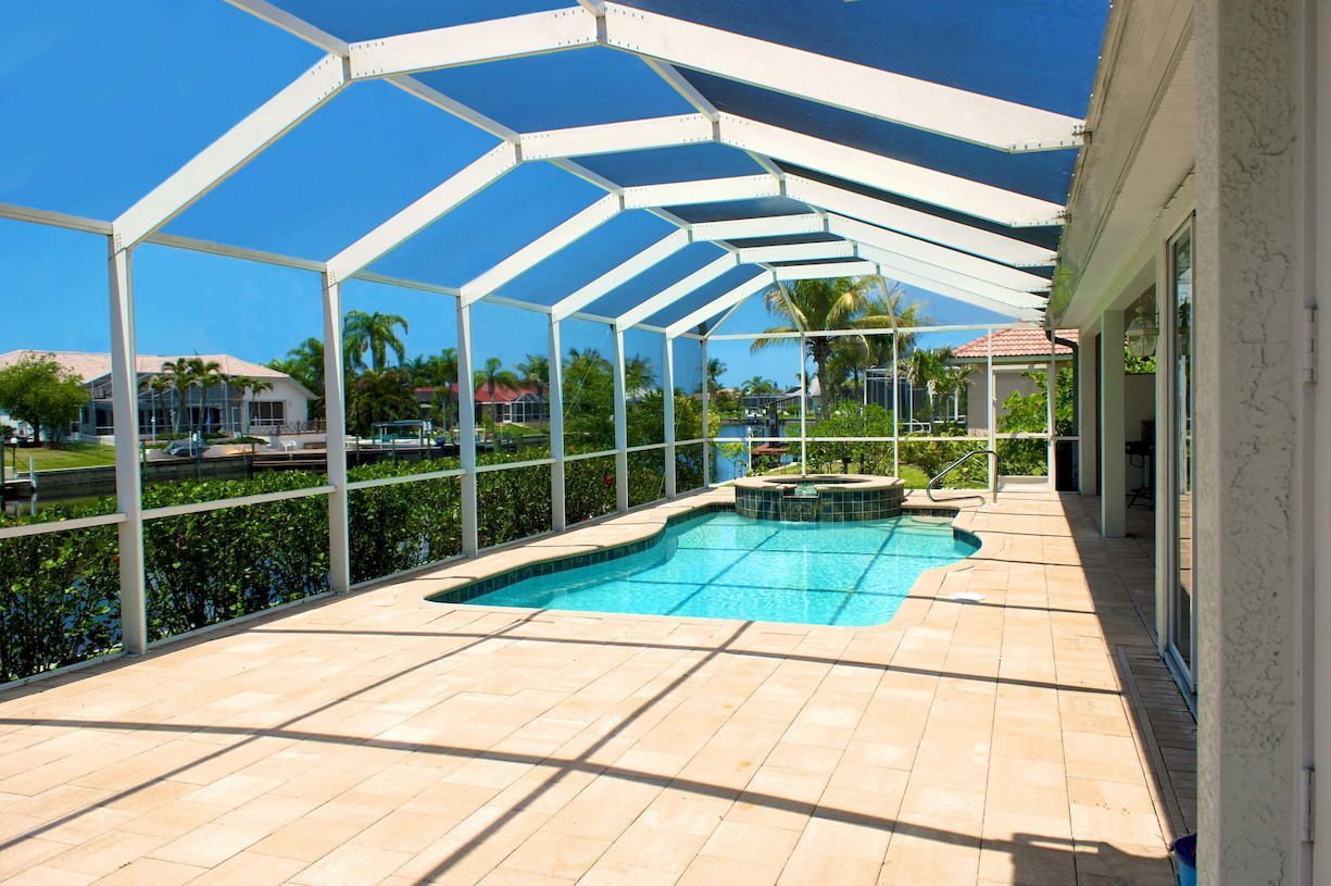 A large swimming pool is surrounded by a screened in area.