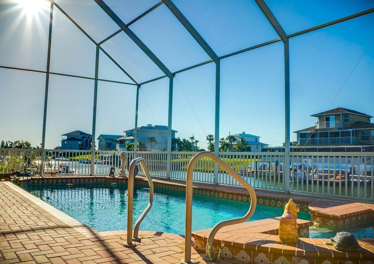 A swimming pool with stairs leading to it and a screened in area.