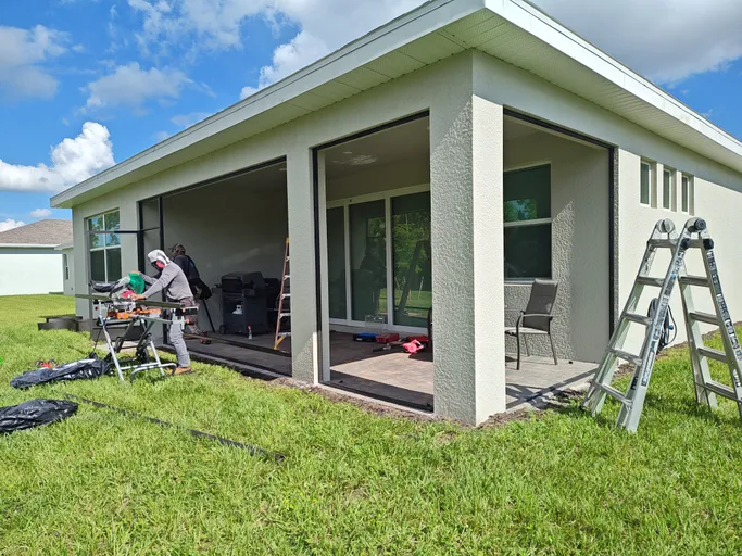 A couple of men are working on a porch in front of a house.