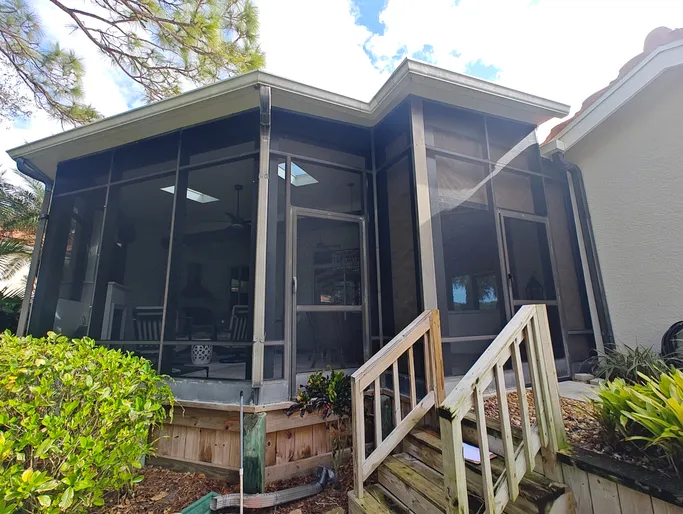A house with a screened in porch and stairs leading up to it.