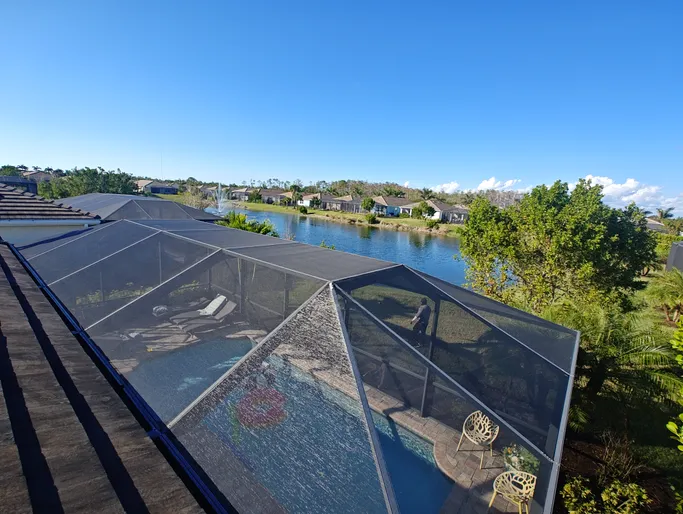 An aerial view of a screened in pool with a view of a lake.