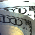 Close-up of overlapping U.S. $100 bills with visible blue security strip and “100” numerals