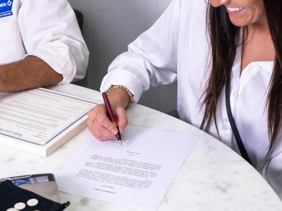 Two people signing documents at a marble table with a notebook and pen