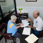 Two people reviewing papers at a desk in an office with a green lamp