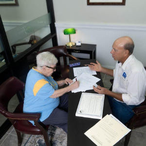 Two people reviewing papers at a desk in an office with a green lamp