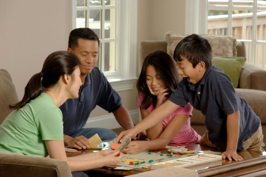 Family playing a board game together at a table in a bright living room