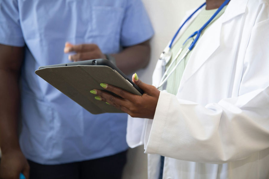 Doctor holding a clipboard and speaking with another person in a blue shirt