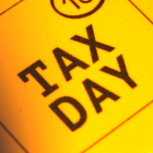 Yellow sign with bold black text reading “TAX DAY” at a diagonal angle