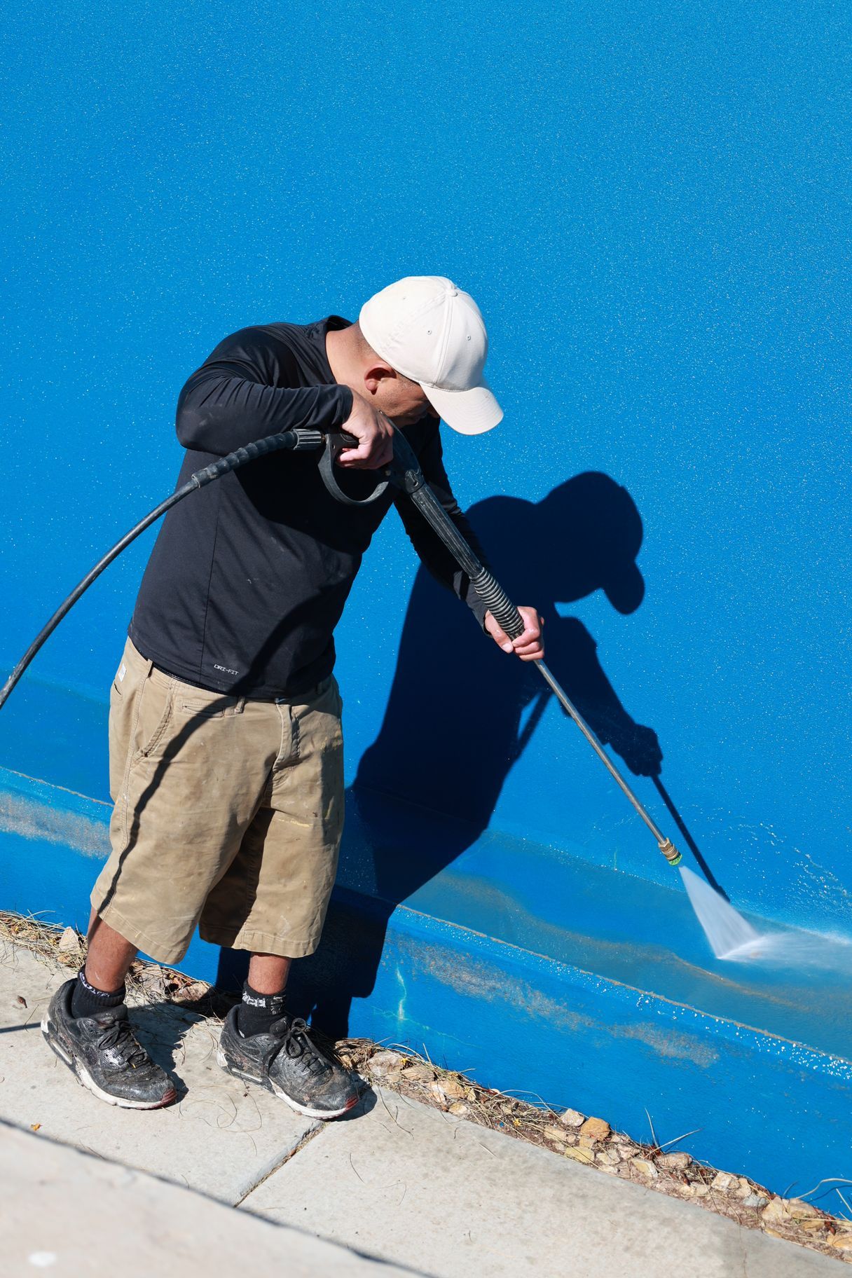 Person painting a bright blue wall with a long-handled roller