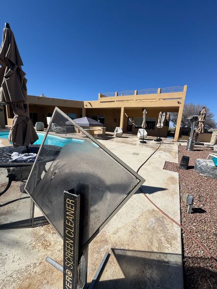 Outdoor desert patio with shade sails, tables, and a beige building under a blue sky
