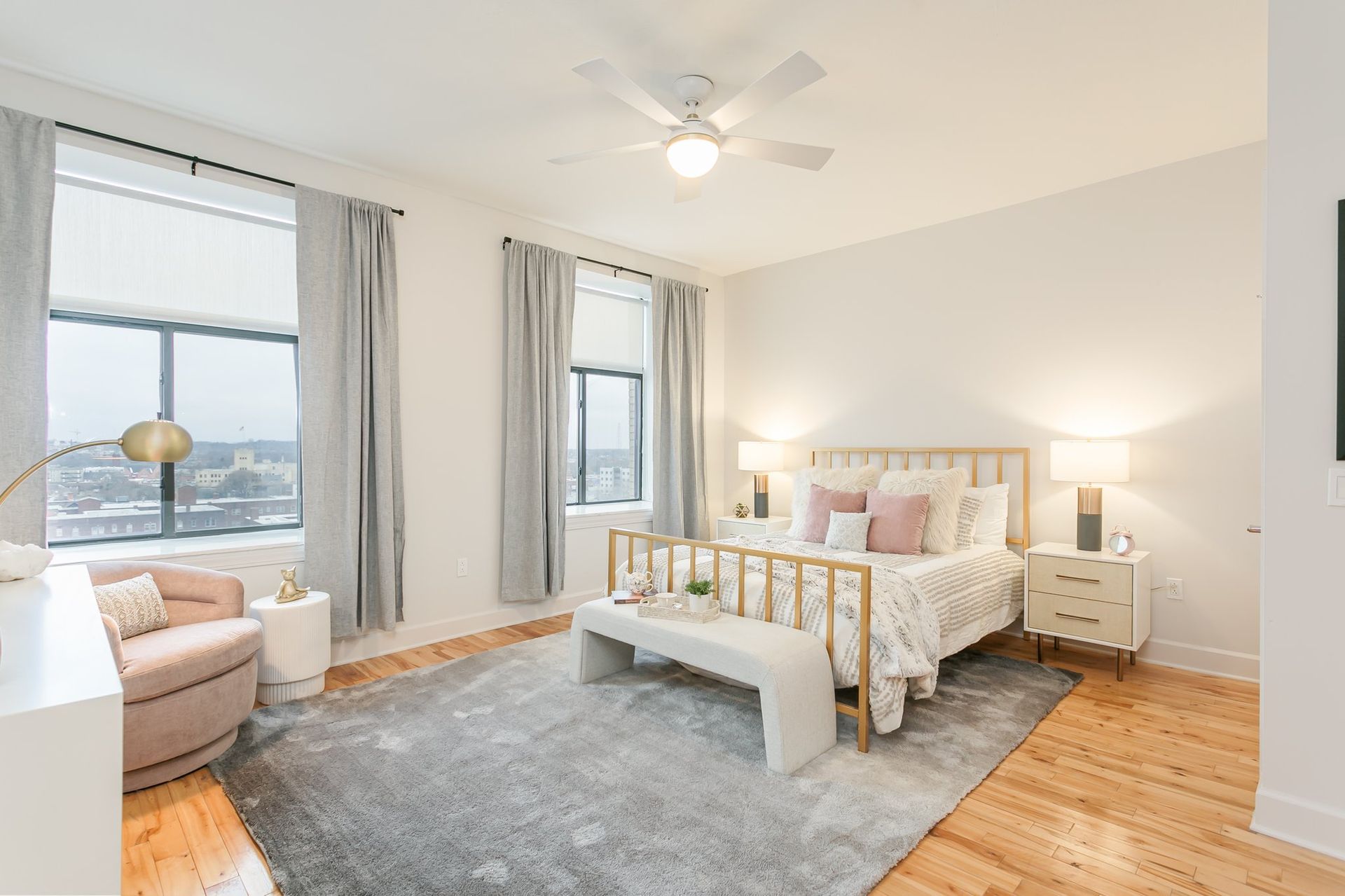 Bedroom with two large windows, hardwood floors, and ceiling fan