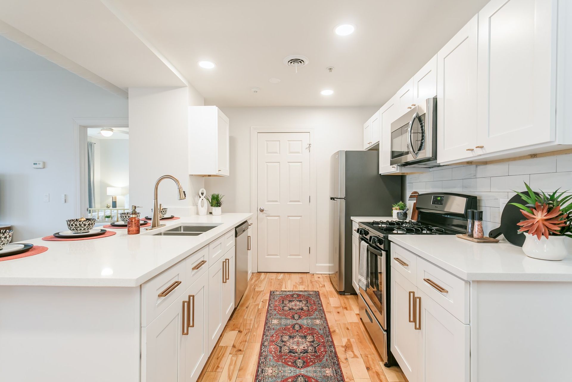 Modern kitchen with stainless steel appliances, marble countertops, and hardwood floors