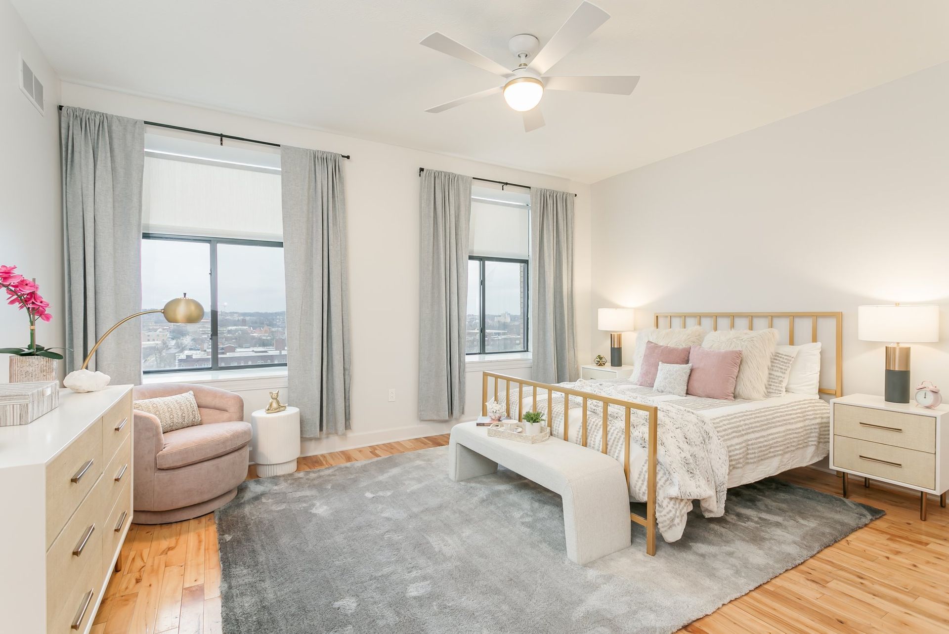 Bedroom with two large windows, hardwood floors, and ceiling fan