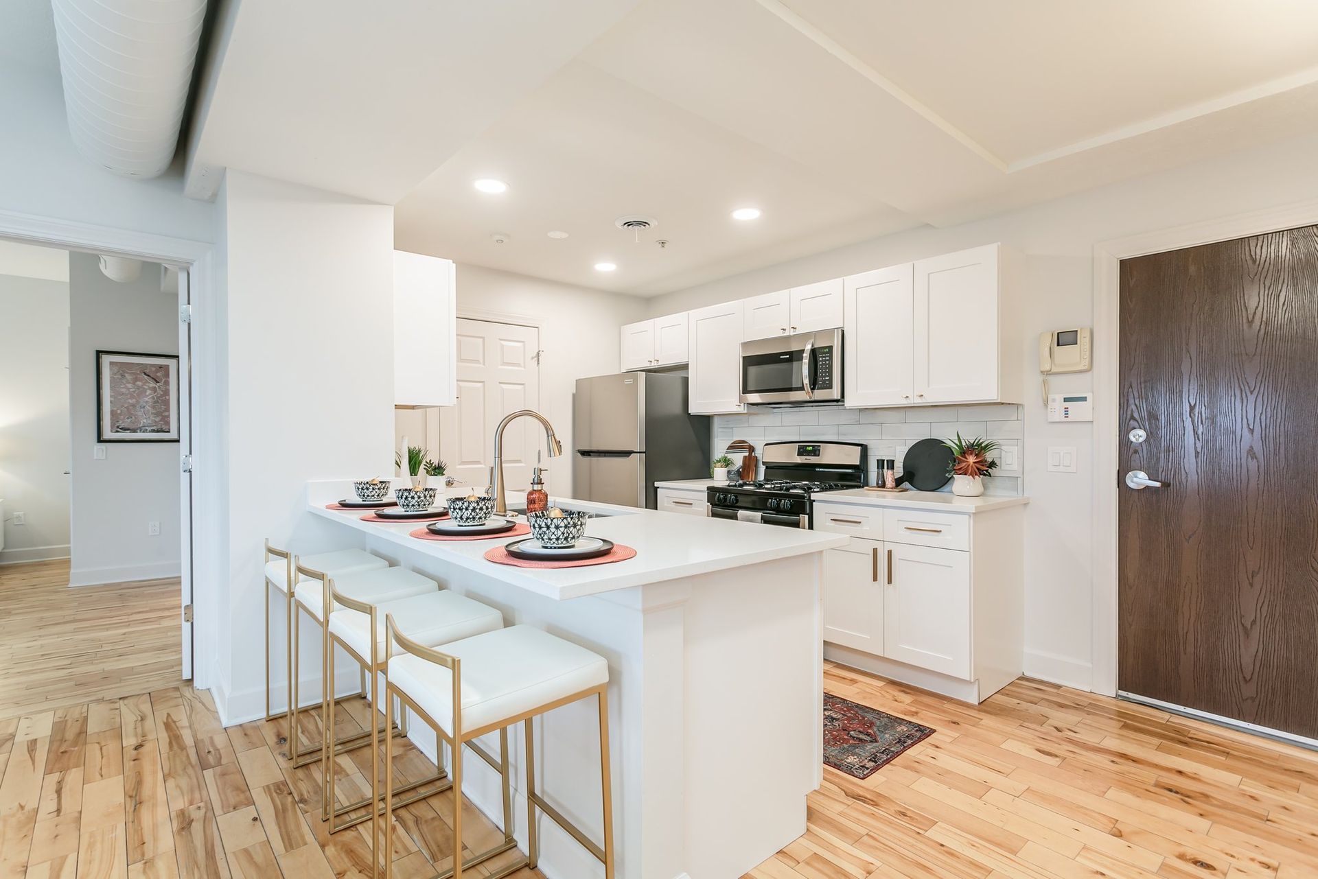 Modern kitchen with stainless steel appliances, marble countertops, breakfast bar, and hardwood floors