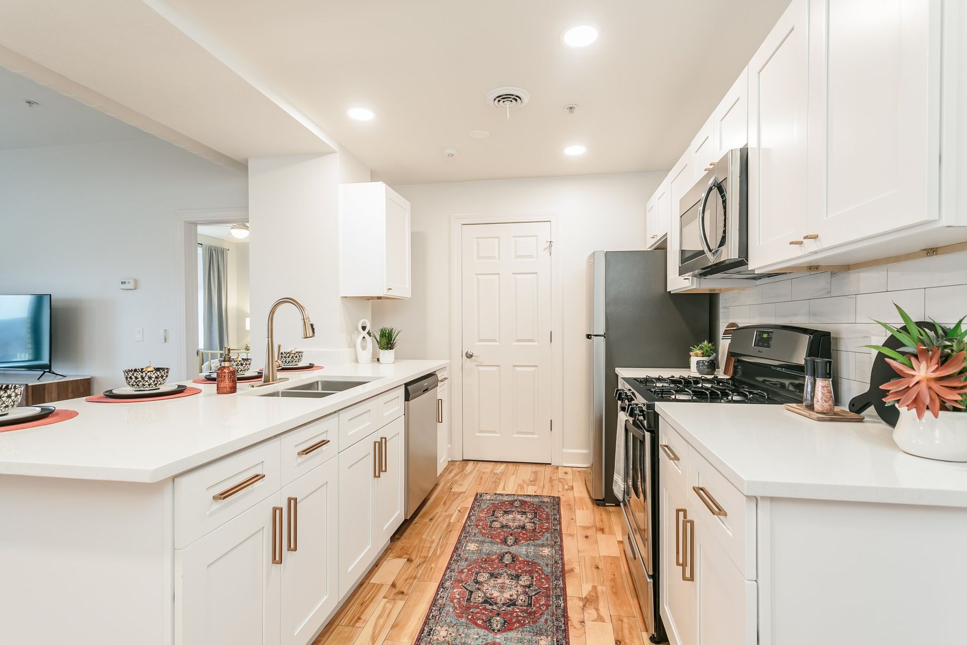 Modern kitchen with stainless steel appliances, marble countertops, and hardwood floors